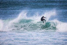 A surfer makes the most of the first waves of spring on a cold day at Blackhead, Dunedin, New Zealand.